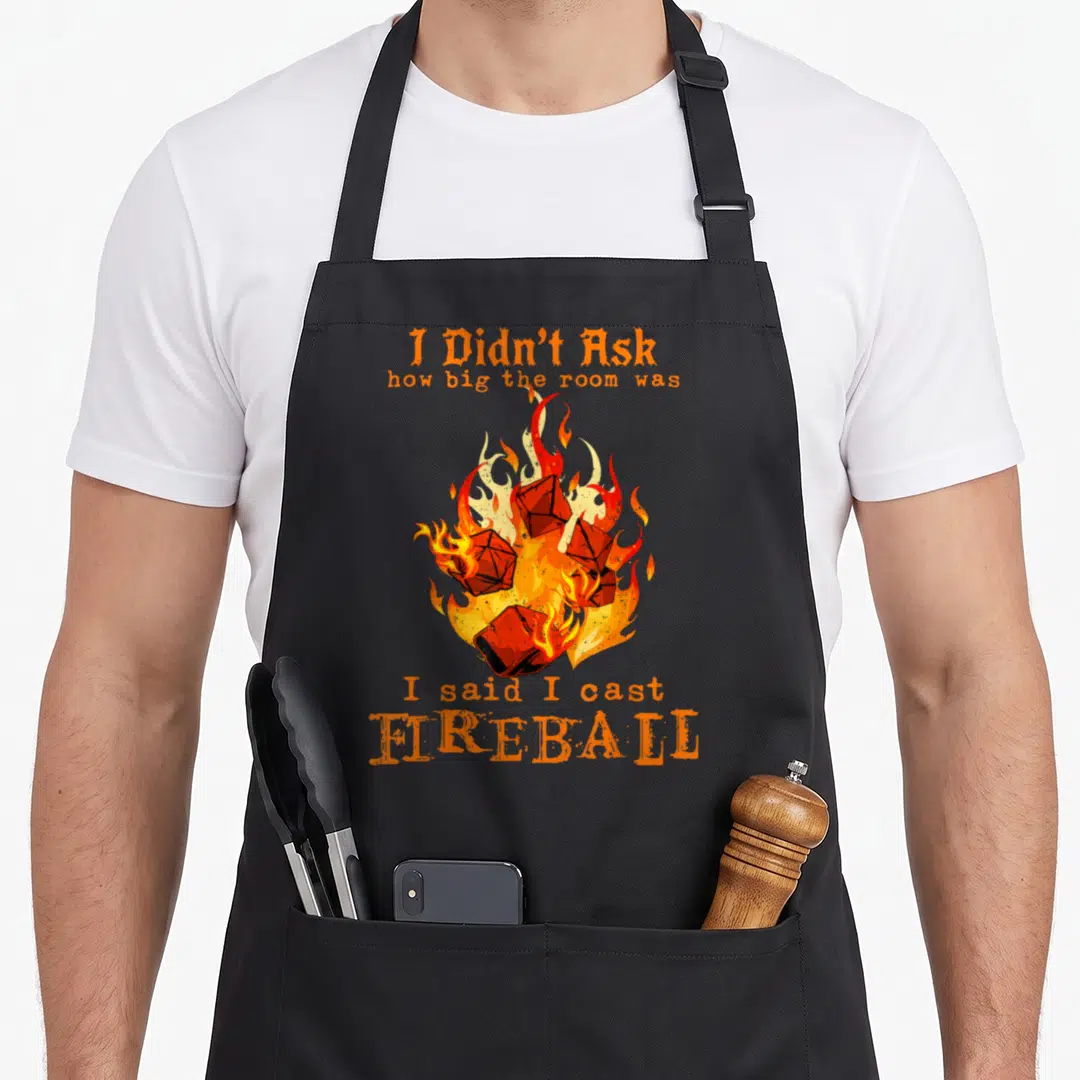 Didnt fireball apron - Burning polyhedral dice surrounded by orange and red flames with sarcastic text — shown on a black cotton canvas apron against a white background