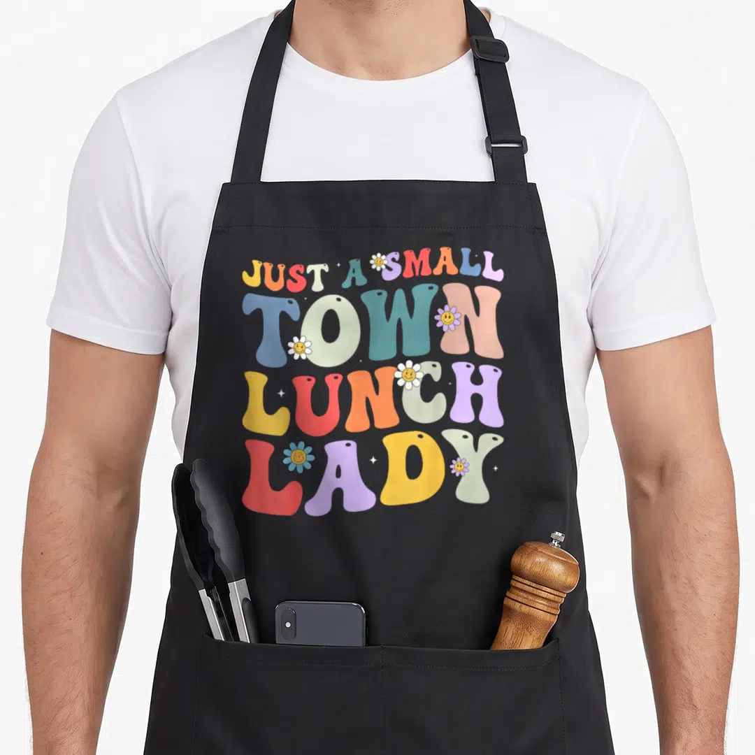 Funny lunch cafeteria aprons - Colorful retro text reading Just A Small Town Lunch Lady surrounded by smiley face — shown on a black cotton canvas apron against a white background