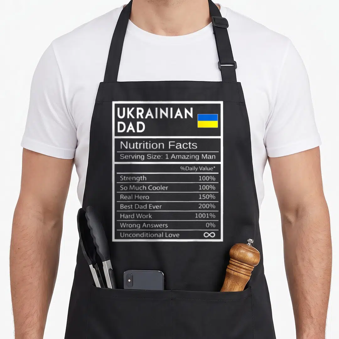 Nutrition ukrainian aprons - Nutrition label graphic listing Strength, Real Hero, and Unconditional Love stats next — shown on a black cotton canvas apron against a white background