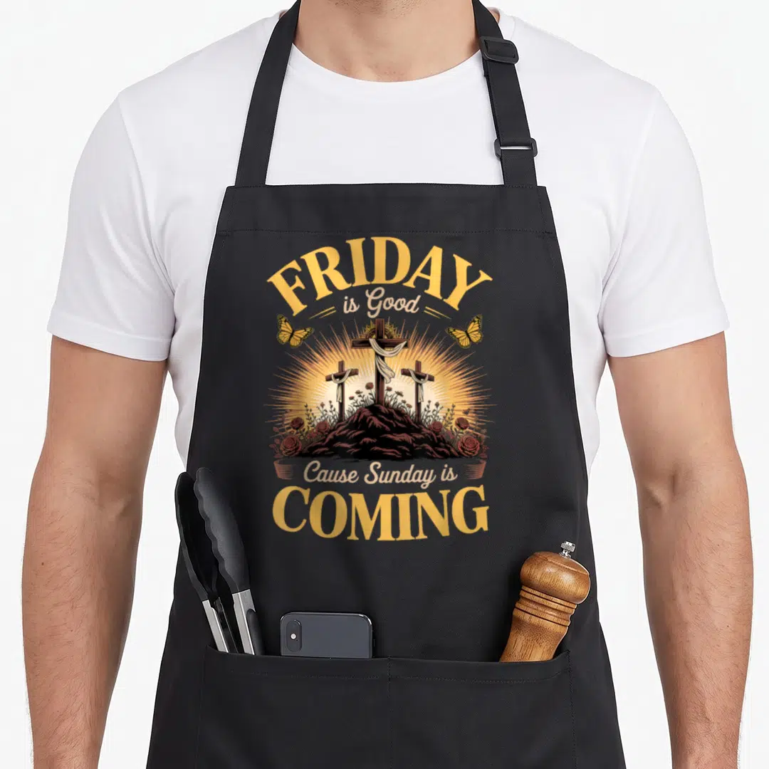 Sunday coming easter apron - Three crosses on a brown hill with red roses and yellow butterflies under arched text — shown on a black cotton canvas apron against a white background