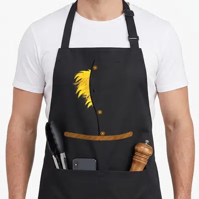 Scarecrow halloween apron - Minimalist yellow wheat stalks overlapping a black line with three brown buttons — shown on a black cotton canvas apron against a white background