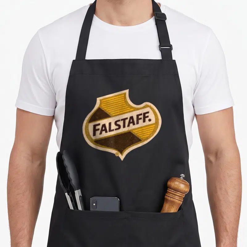 Falstaff beer apron - Retro shield logo with yellow and brown coloring and centered FALSTAFF lettering — shown on a black cotton canvas apron against a white background