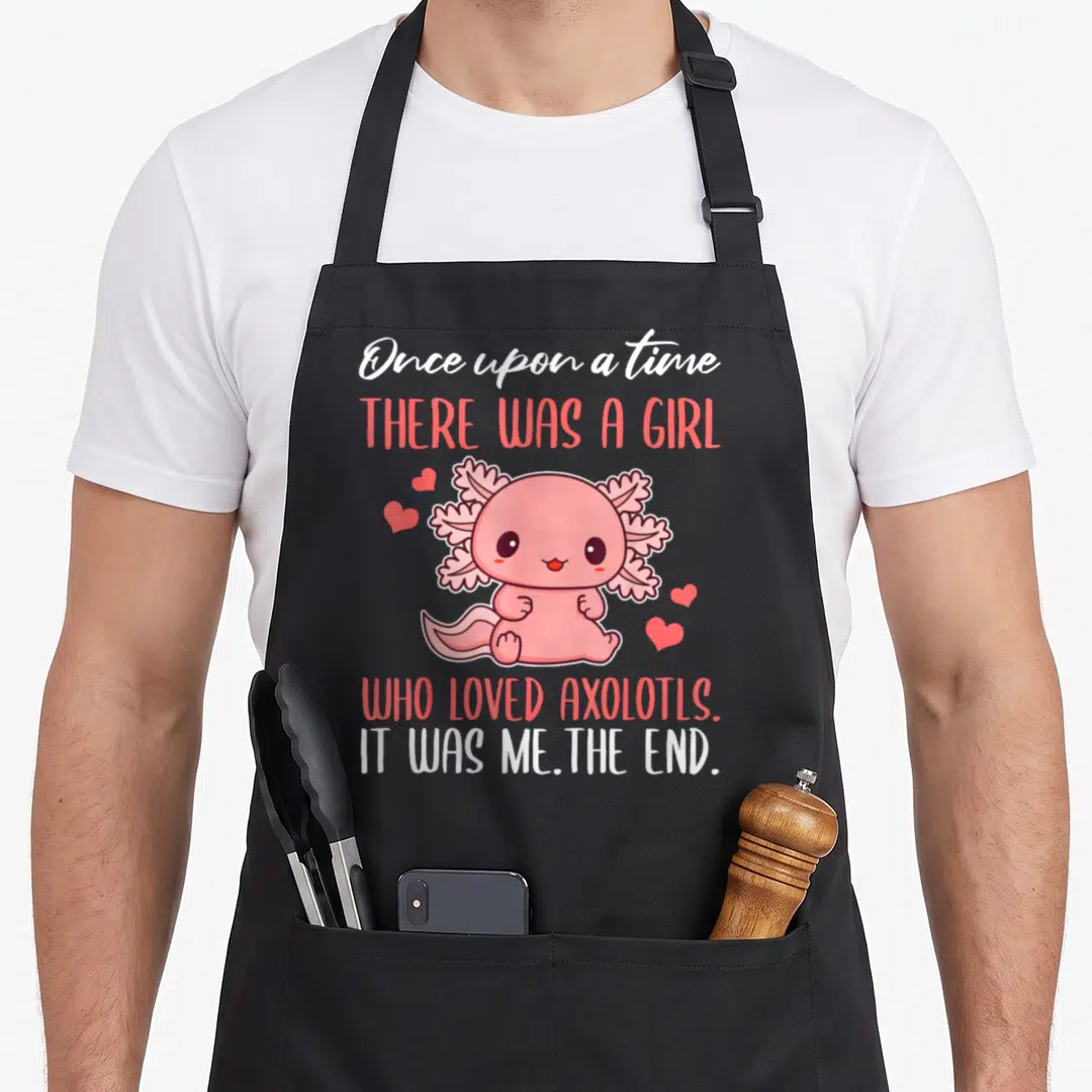 Axolotl once upon an apron - Pink cartoon axolotl surrounded by hearts with stacked text reading It was me The end — shown on a black cotton canvas apron against a white background
