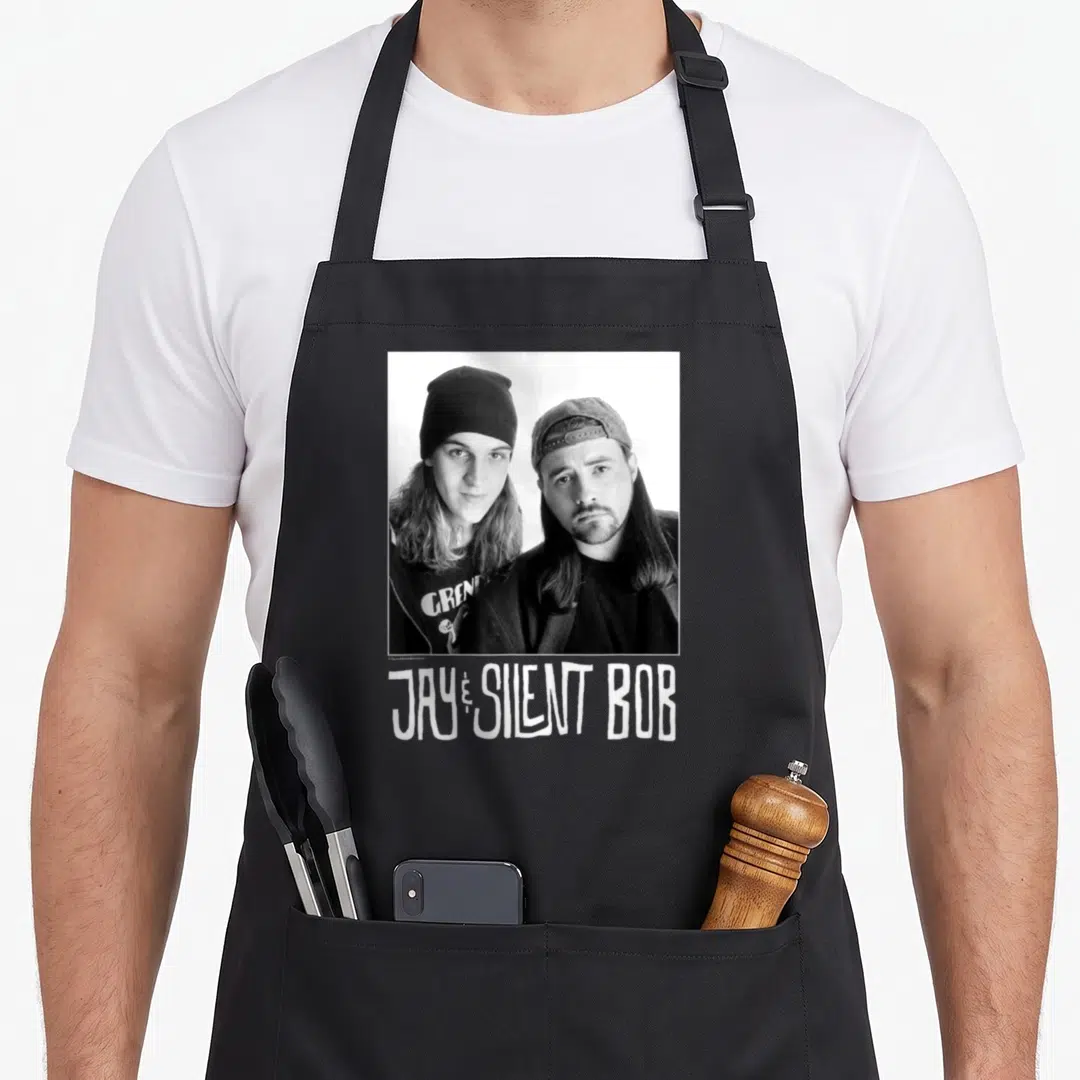 Silent jay lover apron - Grayscale photo of two men with JAY and SILENT BOB text below — shown on a black cotton canvas apron against a white background