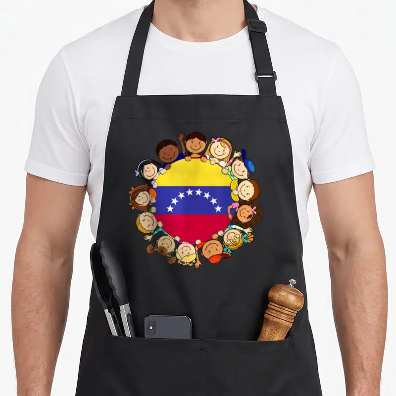 Venezuela venezuelan hispanic aprons - Cartoon children surrounding a circular Venezuelan flag in yellow blue red — shown on a black cotton canvas apron against a white background