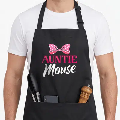 Auntie mouse mothers apron - Pink polka dot bow above AUNTIE Mouse text in cartoon style — shown on a black cotton canvas apron against a white background