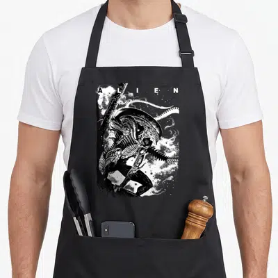 Alien iconic aprons - A L I E N text above Xenomorph line art with white smoke and tail — shown on a black cotton canvas apron against a white background