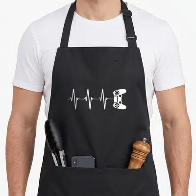 Pulse video game apron - White heartbeat line connecting to a game controller in minimalist style — shown on a black cotton canvas apron against a white background