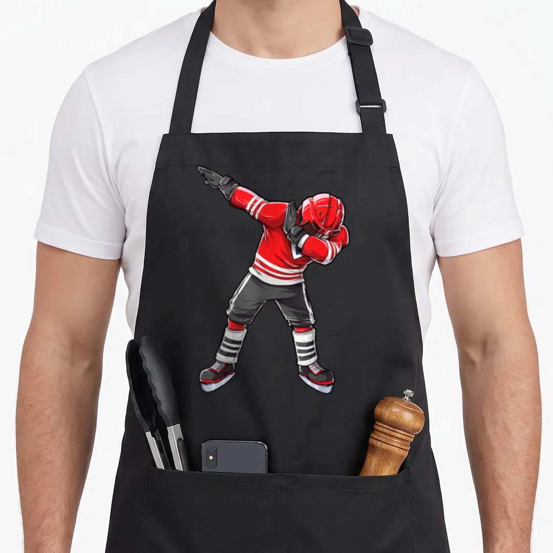 Dab hockey apron - Cartoon hockey player in red jersey performing a dab pose with black pants and skates — shown on a black cotton canvas apron against a white background