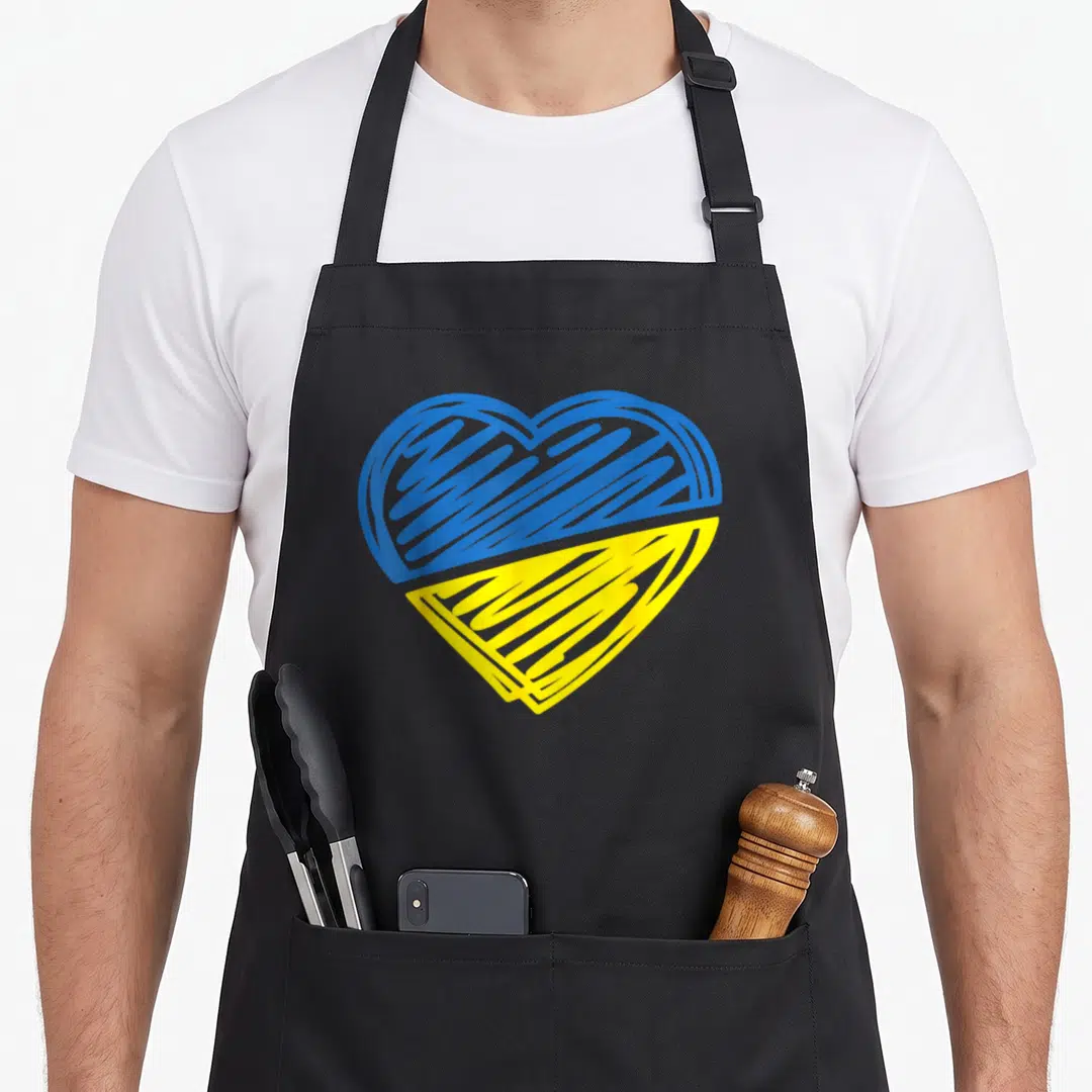 Ukraine flag ukrainian aprons - Blue and yellow scribbled heart shape on black fabric — shown on a black cotton canvas apron against a white background