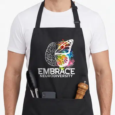 Embrace adhd apron - White brain and rainbow butterfly wing graphic above EMBRACE NEURODIVERSITY text — shown on a black cotton canvas apron against a white background
