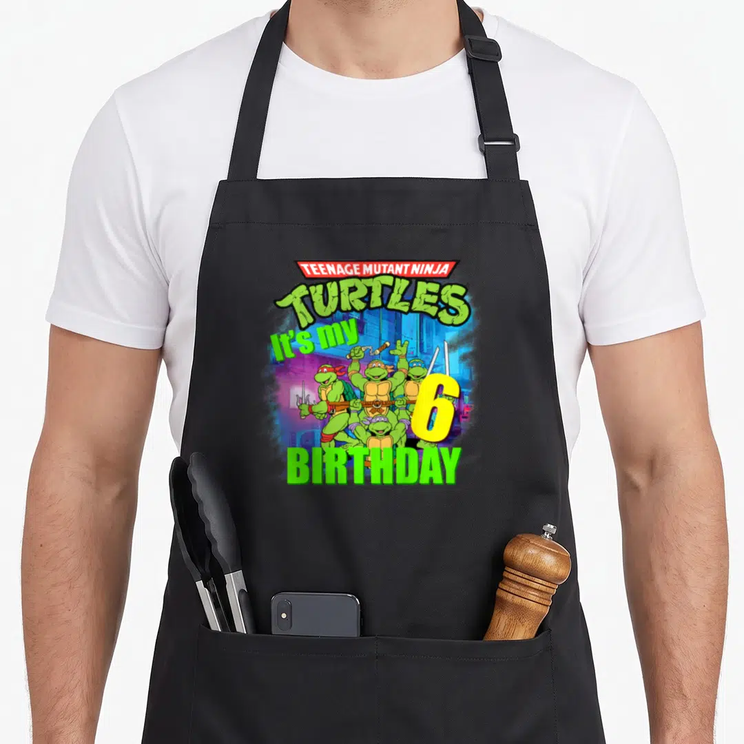 Mademark teenage cooking aprons - Teenage Mutant Ninja Turtles cartoon with It's my 6 BIRTHDAY text and large yellow — shown on a black cotton canvas apron against a white background