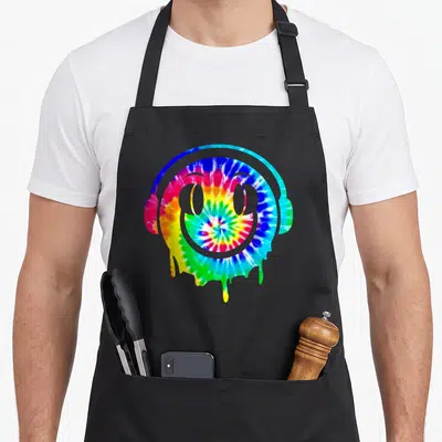 Melting tie-dye apron - Tie-dye smiley face with headphones dripping blue green yellow red purple colors — shown on a black cotton canvas apron against a white background