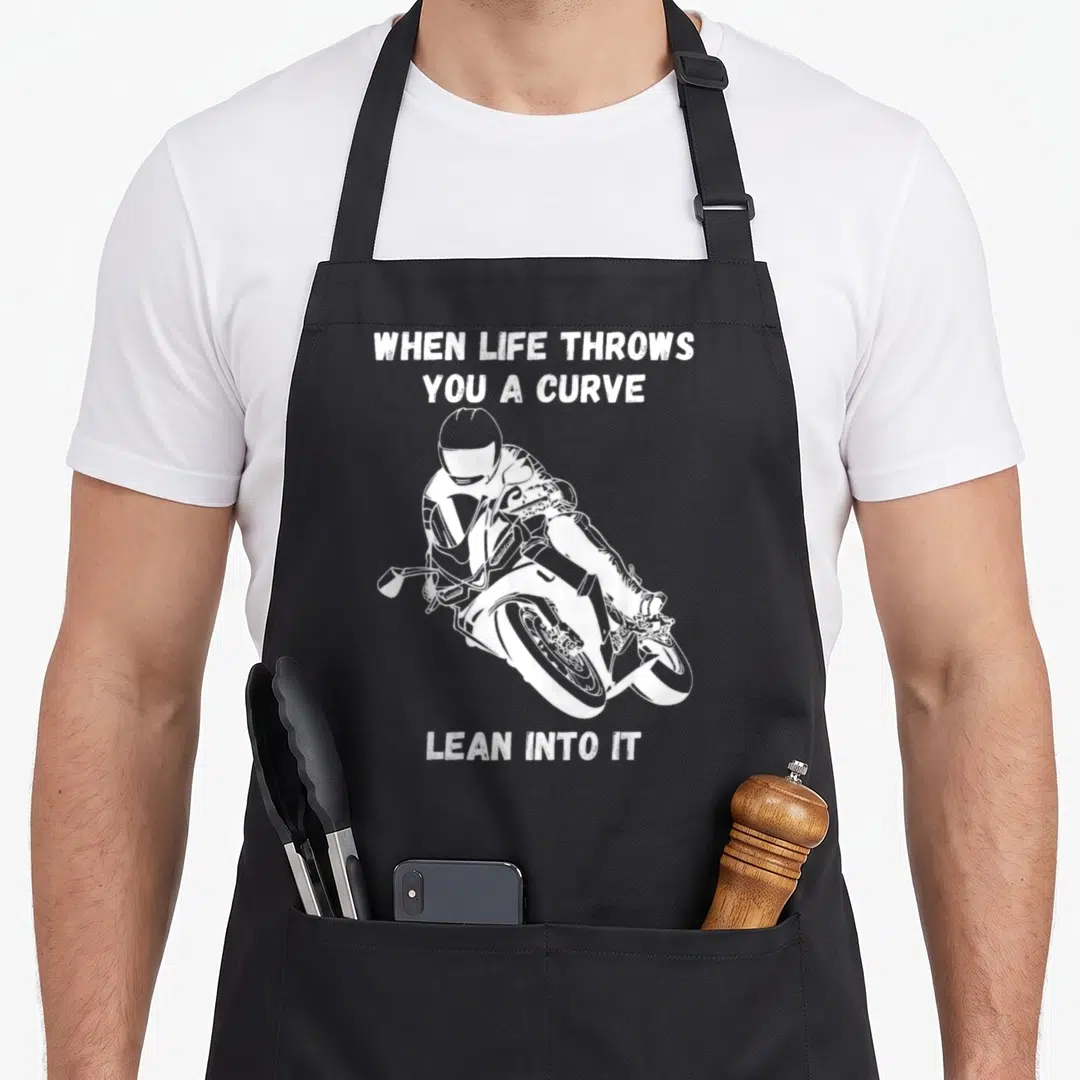 Curve motorcycle apron - White distressed text and motorcyclist leaning on bike with split layout — shown on a black cotton canvas apron against a white background