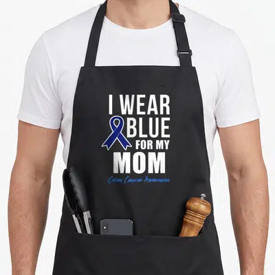 Colon crab dad apron - I WEAR BLUE FOR MY MOM text with dark blue ribbon and Colon Cancer Awareness script — shown on a black cotton canvas apron against a white background