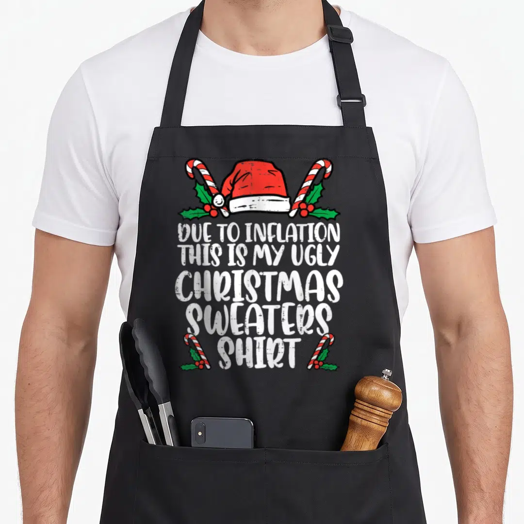 Due christmas apron - Santa hat and candy canes surrounding due to inflation ugly Christmas sweater shirt text — shown on a black cotton canvas apron against a white background