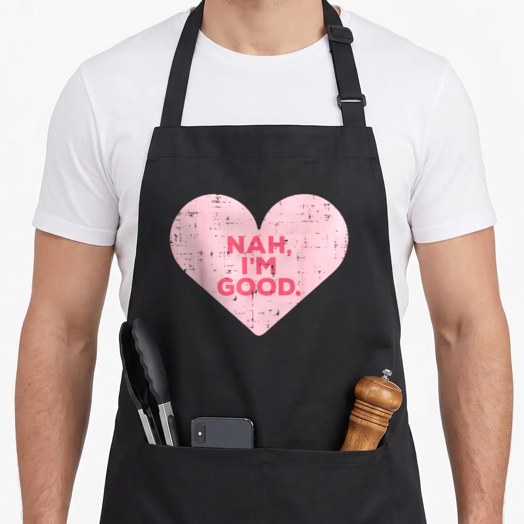 Nah valentine's day apron - Pink heart with red stacked text NAH I'M GOOD in distressed font — shown on a black cotton canvas apron against a white background