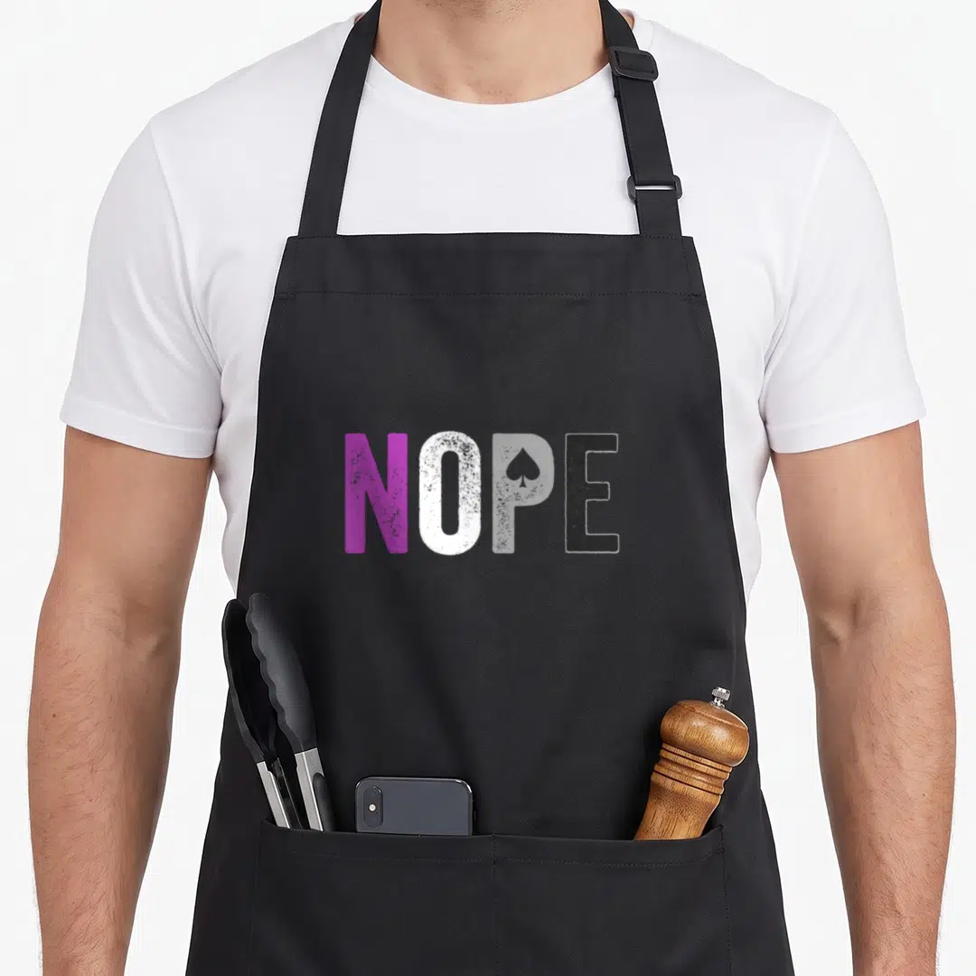 Nope pride apron - Purple white grey and black NOPE text with spade symbol representing asexual pride — shown on a black cotton canvas apron against a white background