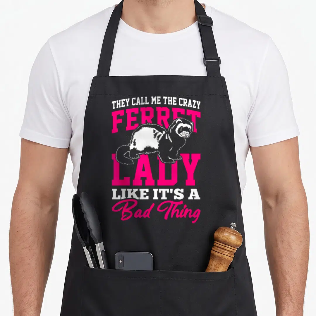 Crazy ferret lady apron for men - Stacked pink and white text with a cartoon ferret illustration on a black background — shown on a black cotton canvas apron against a white background