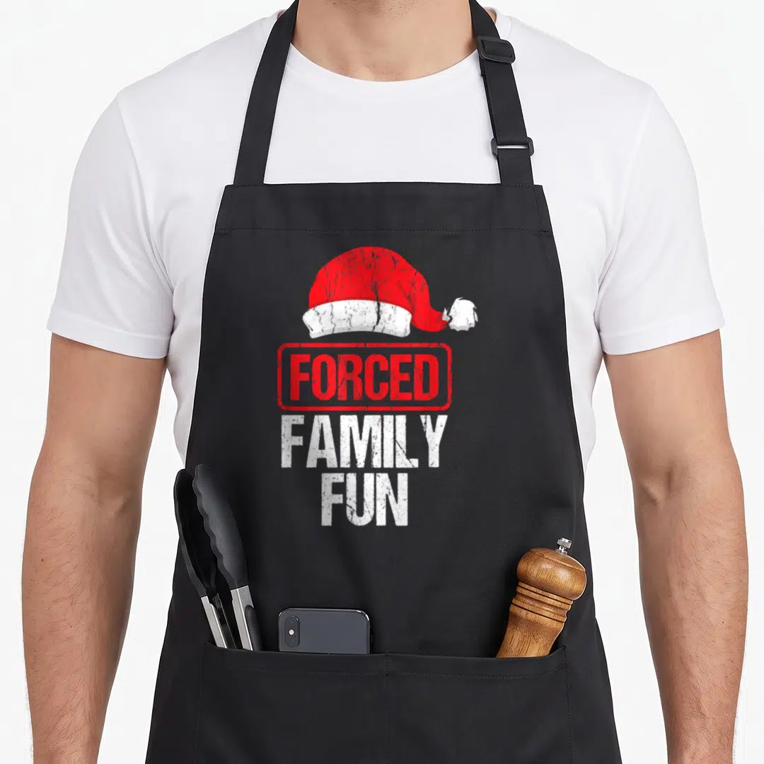 Forced winter apron - Distressed red Santa hat above stamped FORCED FAMILY FUN text in red and white — shown on a black cotton canvas apron against a white background