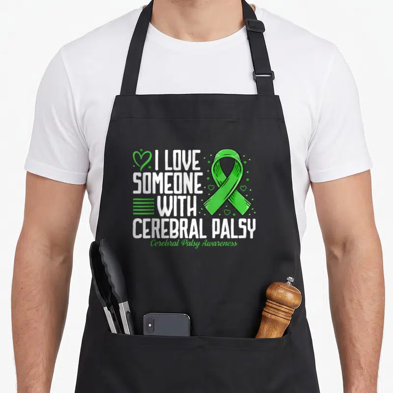 Someone cerebral palsy awareness apron - White text I Love Someone With Cerebral Palsy next to a green awareness ribbon — shown on a black cotton canvas apron against a white background