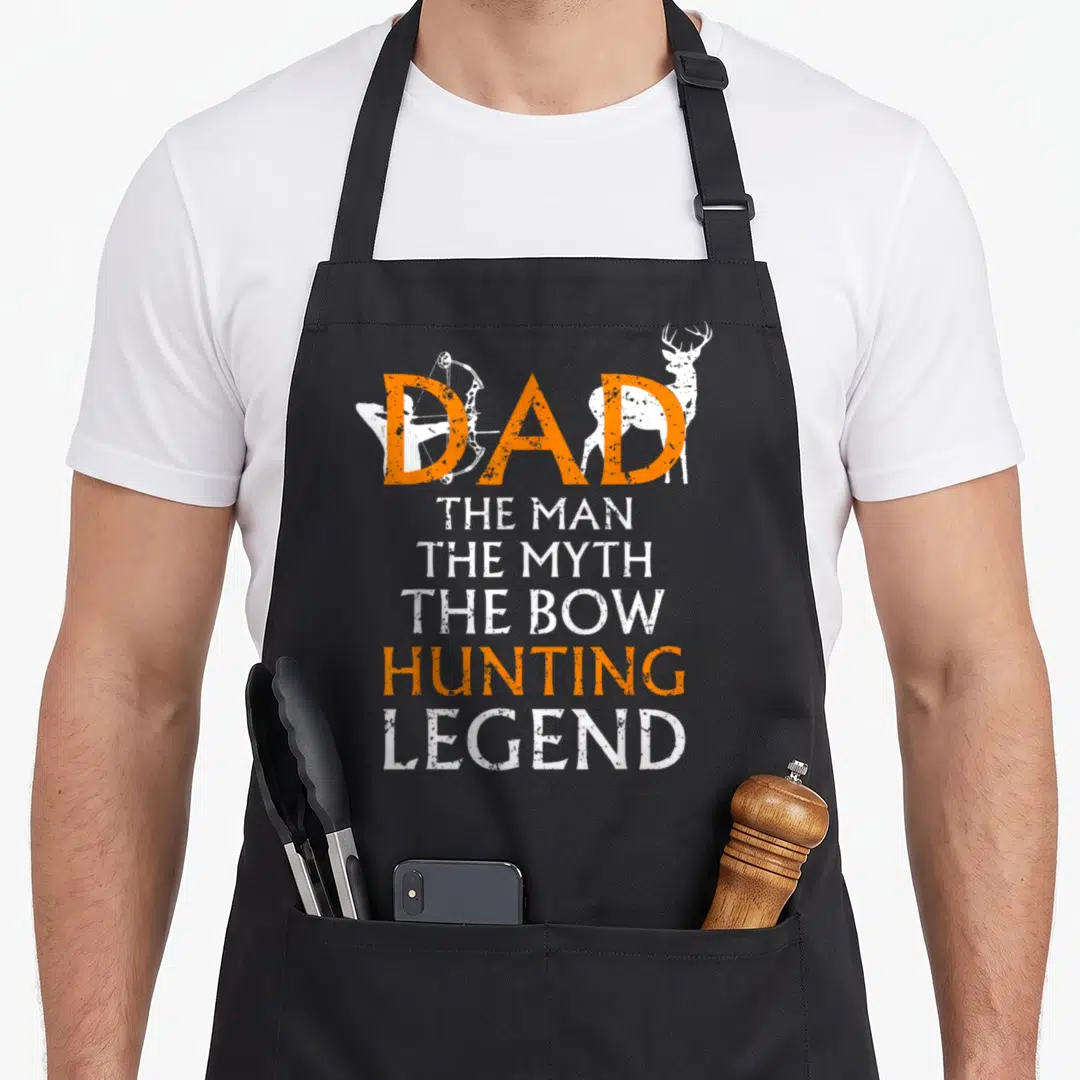 Deer hunting bow apron - Dad The Man The Myth The Bow Hunting Legend text with orange and white deer and bow graphics — shown on a black cotton canvas apron against a white background