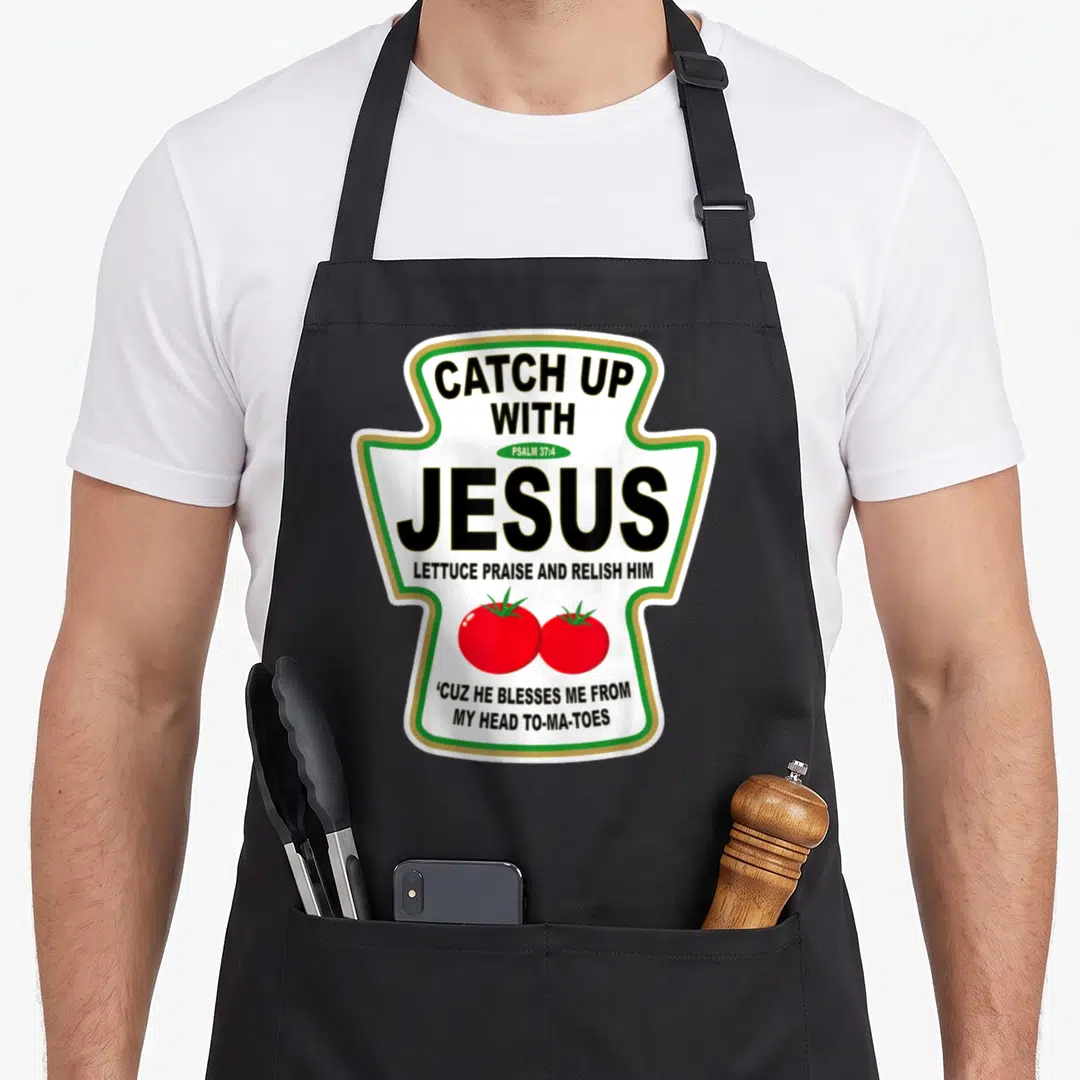 Christian catch up with jesus apron - Ketchup bottle shaped print with text Catch Up With Jesus and two red tomatoes — shown on a black cotton canvas apron against a white background