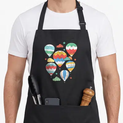 Hot air balloon apron - Six striped hot air balloons in blue red yellow green and white with clouds and stars — shown on a black cotton canvas apron against a white background