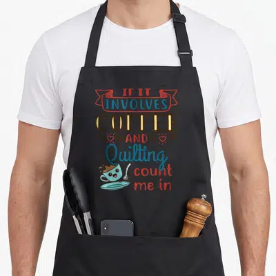 Coffee craft apron - Stacked text with cartoon coffee cup, hearts, beans, red blue brown colors — shown on a black cotton canvas apron against a white background