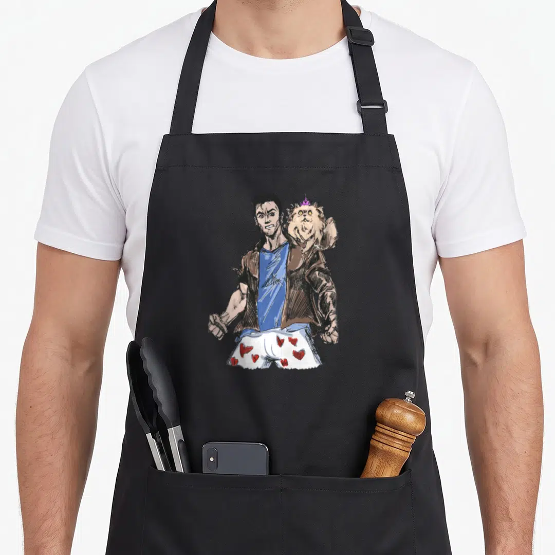 Dungeon princess apron - Muscular man in brown jacket blue shirt white heart shorts with crowned dog perched on shoulder — shown on a black cotton canvas apron against a white background