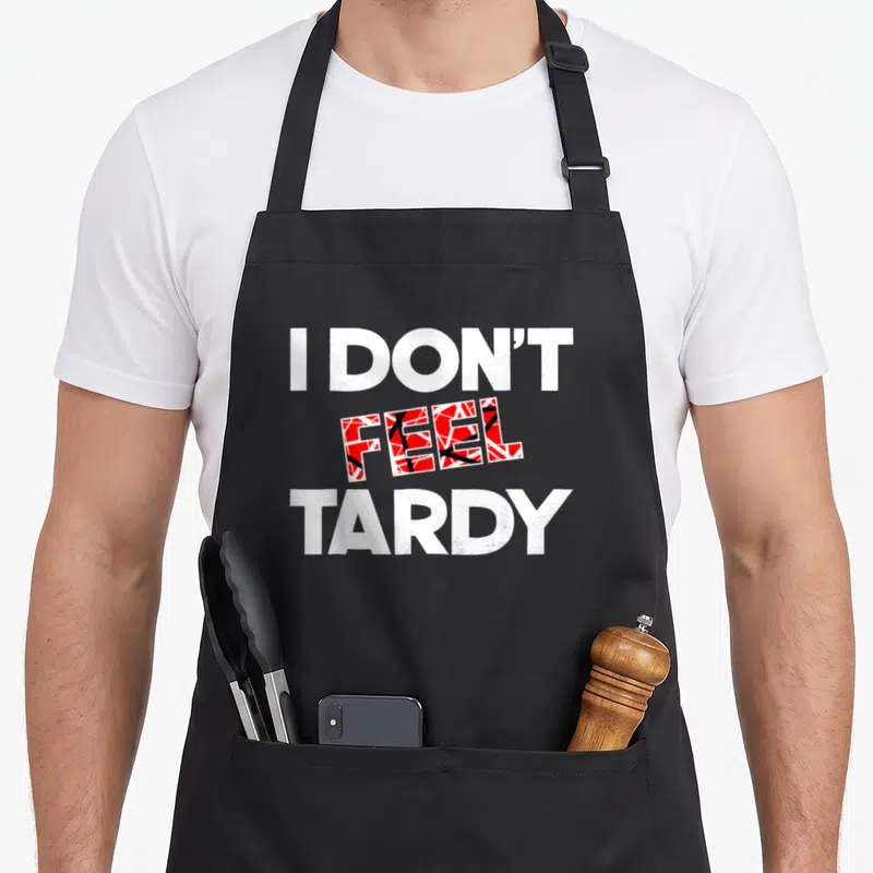 Feel rock apron - Stacked white and red text reading I Don't Feel Tardy with shattered pattern in middle word — shown on a black cotton canvas apron against a white background