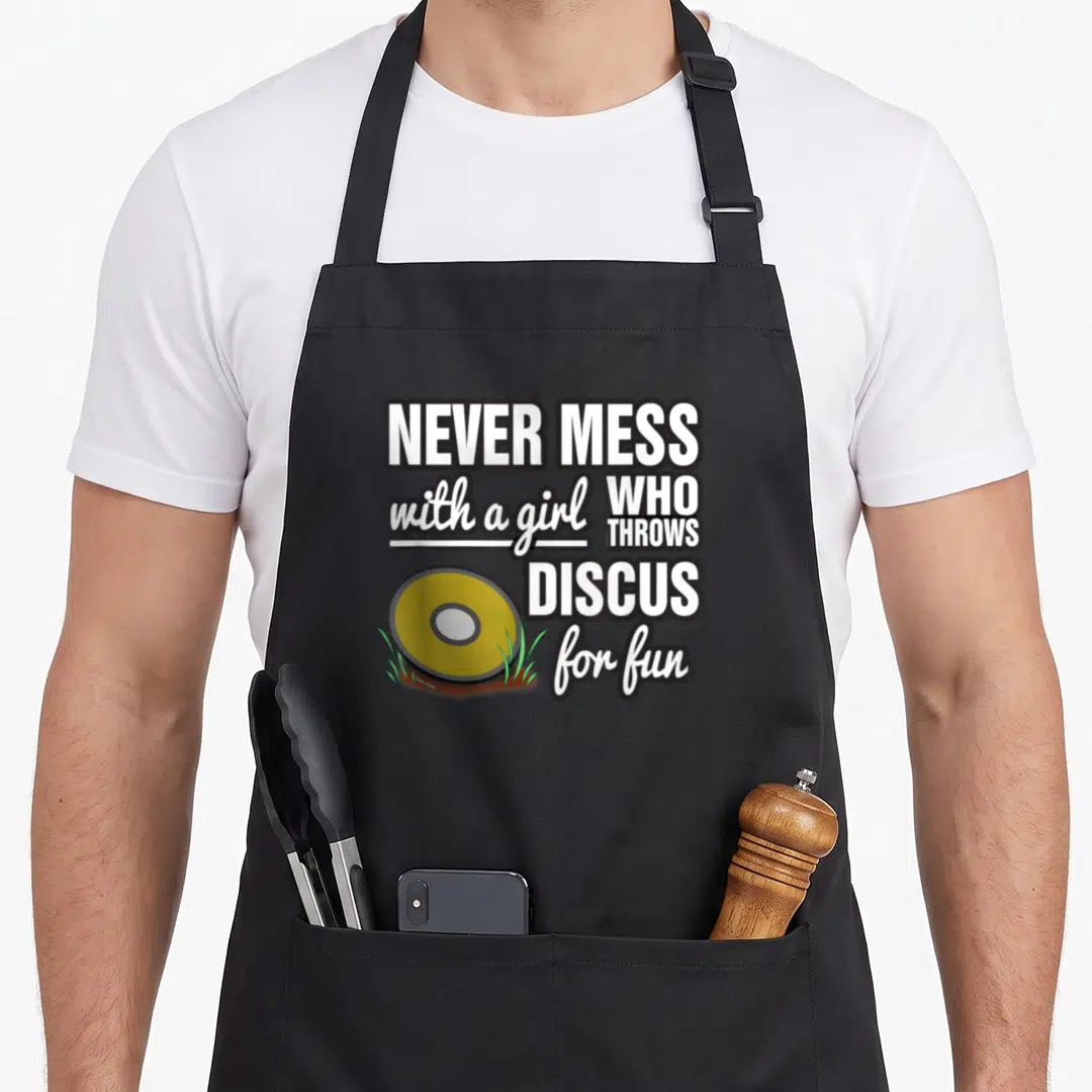 Discus thrower track apron - NEVER MESS text with yellow discus and green grass patches — shown on a black cotton canvas apron against a white background
