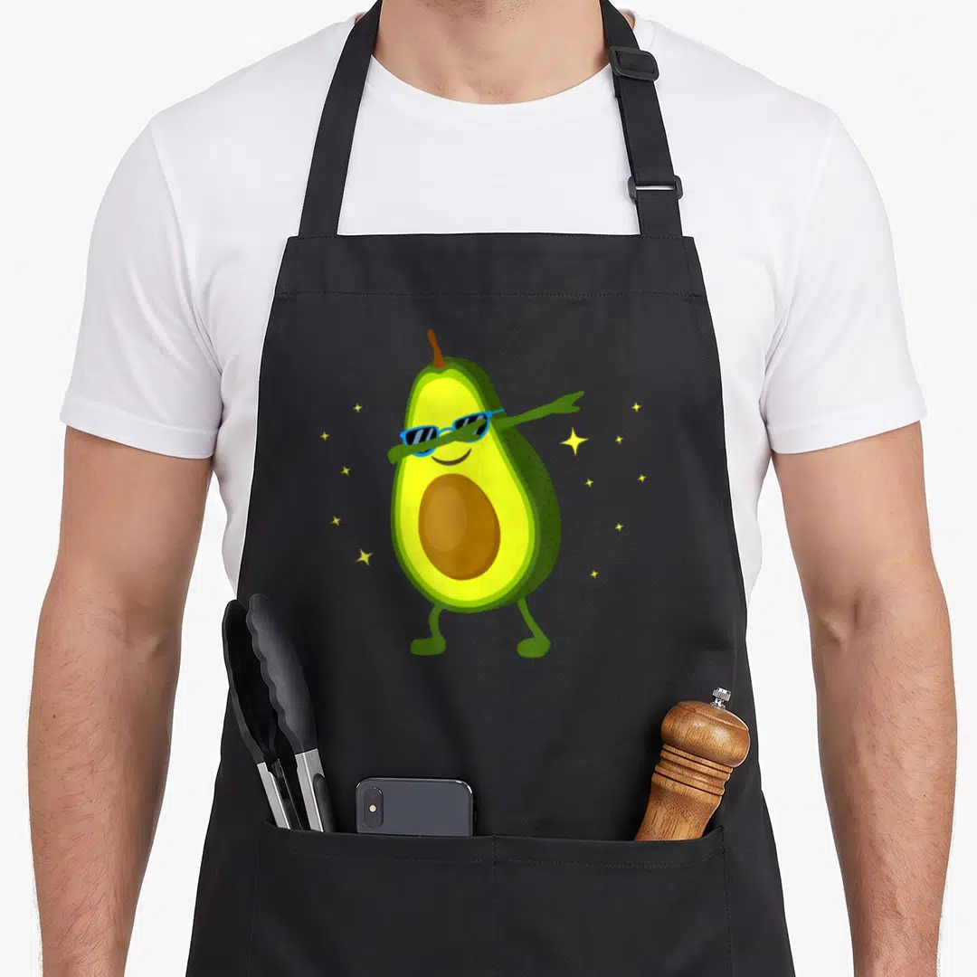 Fruit avocado apron - Cartoon avocado dabbing with blue sunglasses and yellow stars on black background — shown on a black cotton canvas apron against a white background