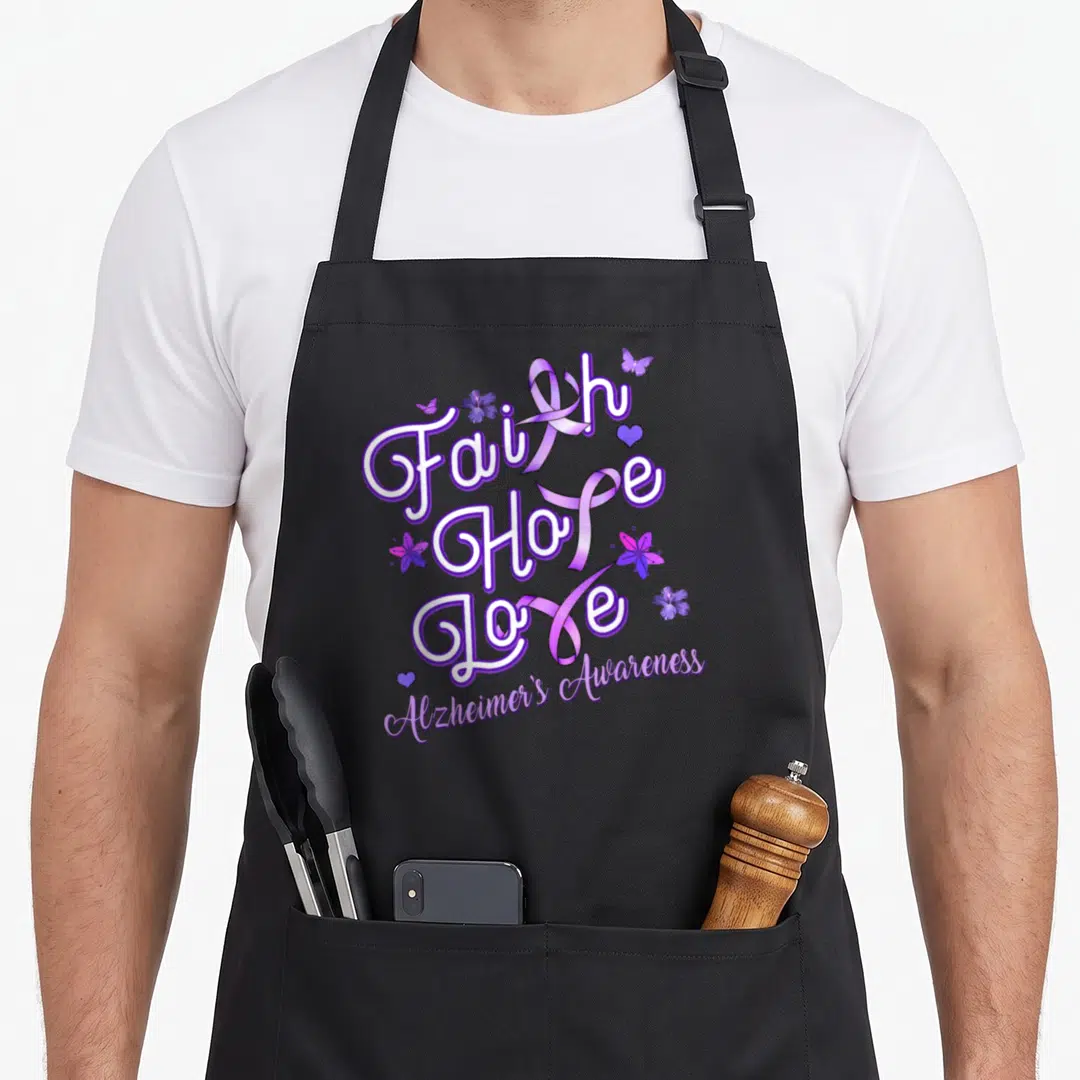 Alzheimer ribbon apron - Faith Hope Love text with purple ribbons, flowers, butterflies, and hearts curved Alzheimer's — shown on a black cotton canvas apron against a white background