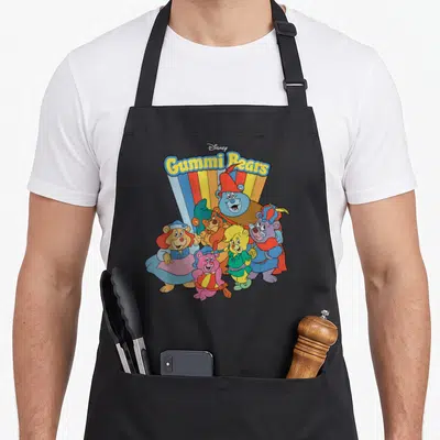 Adventure bear apron - Five cartoon bears under Gummi Bears text with multi-colored sunburst rays — shown on a black cotton canvas apron against a white background