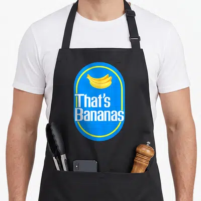 Bananas halloween apron - Blue oval with yellow border containing bananas and white text That's Bananas — shown on a black cotton canvas apron against a white background