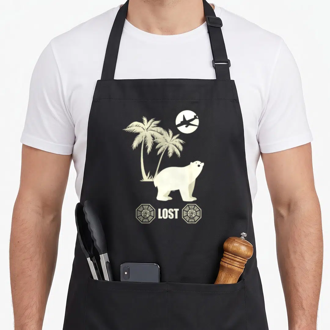 Lost bear apron - Minimalist polar bear stands near two palm trees under a flying plane above LOST text and octagon — shown on a black cotton canvas apron against a white background