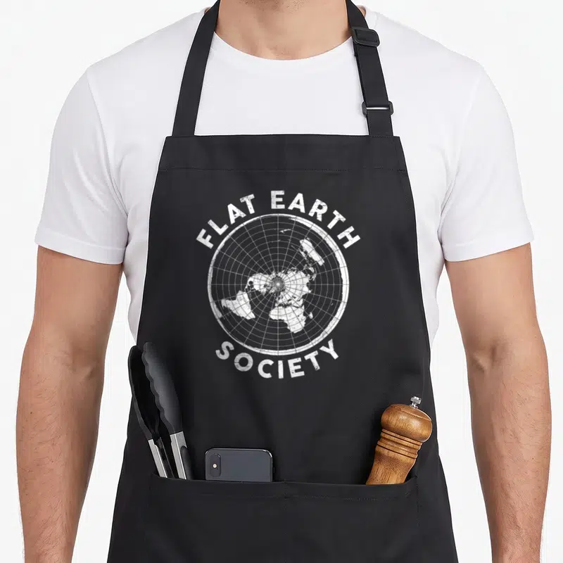 Conspiracy earther apron - White distressed flat earth society map with circular grid and arched text — shown on a black cotton canvas apron against a white background