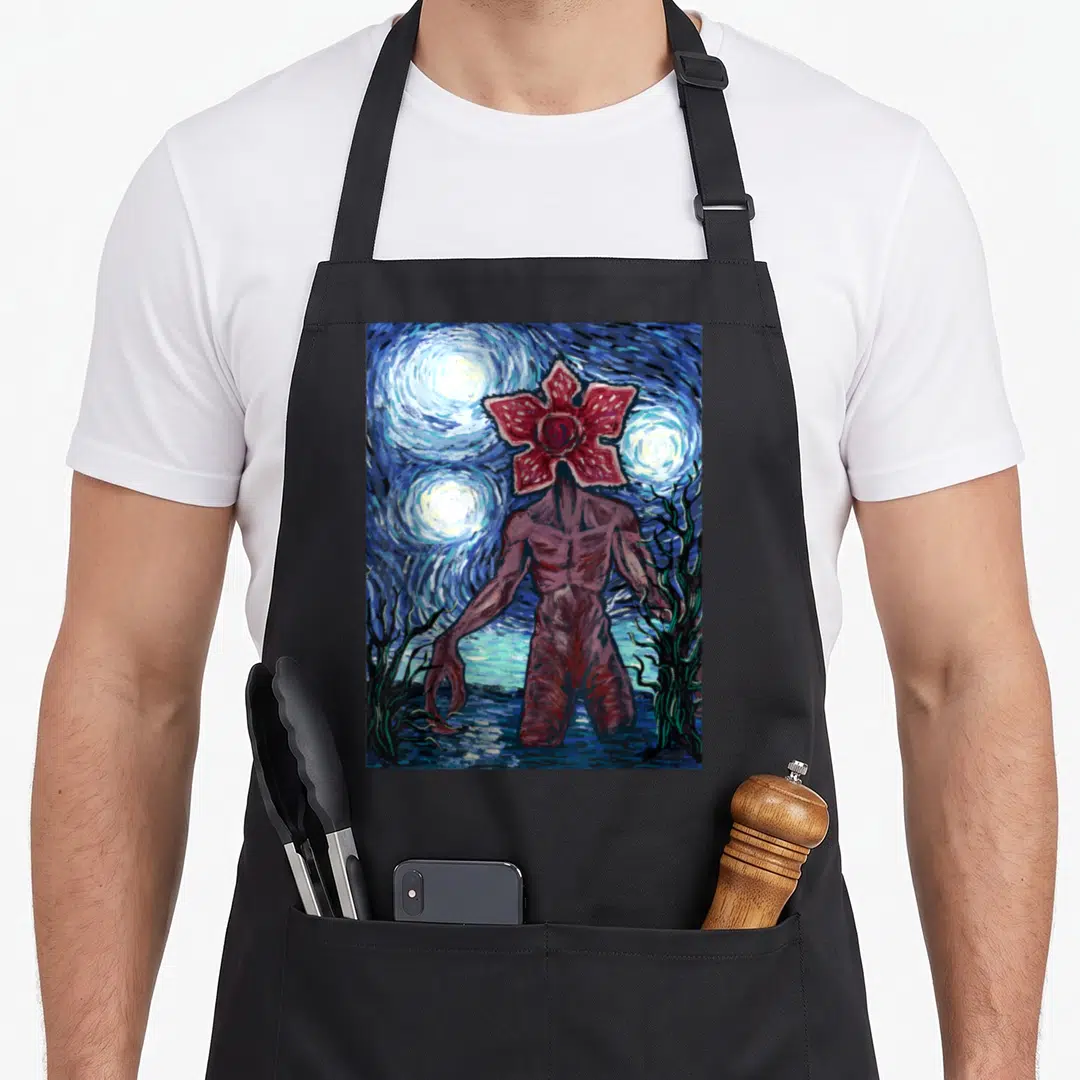 Demogorgon starry night apron - Red flower-headed monster in swirling blue night sky with yellow stars watercolor style — shown on a black cotton canvas apron against a white background