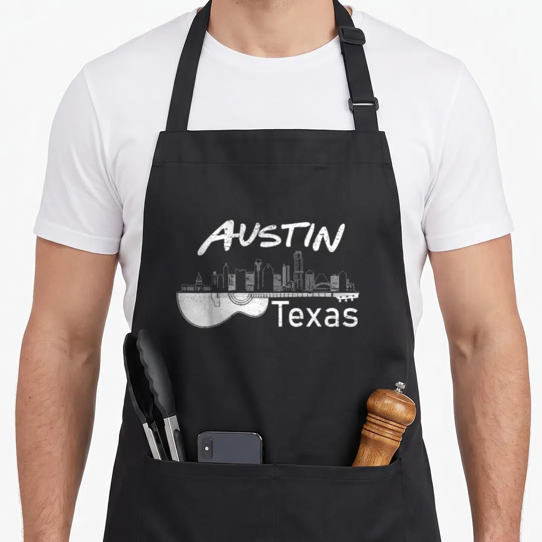Music texas aprons - Distressed white Austin Texas skyline shaped like a guitar on black apron — shown on a black cotton canvas apron against a white background