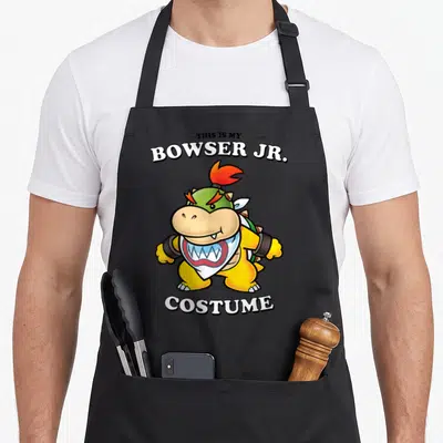 Bro halloween apron - Cartoon Bowser Jr. in yellow and green with white text THIS IS MY BOWSER JR. COSTUME — shown on a black cotton canvas apron against a white background