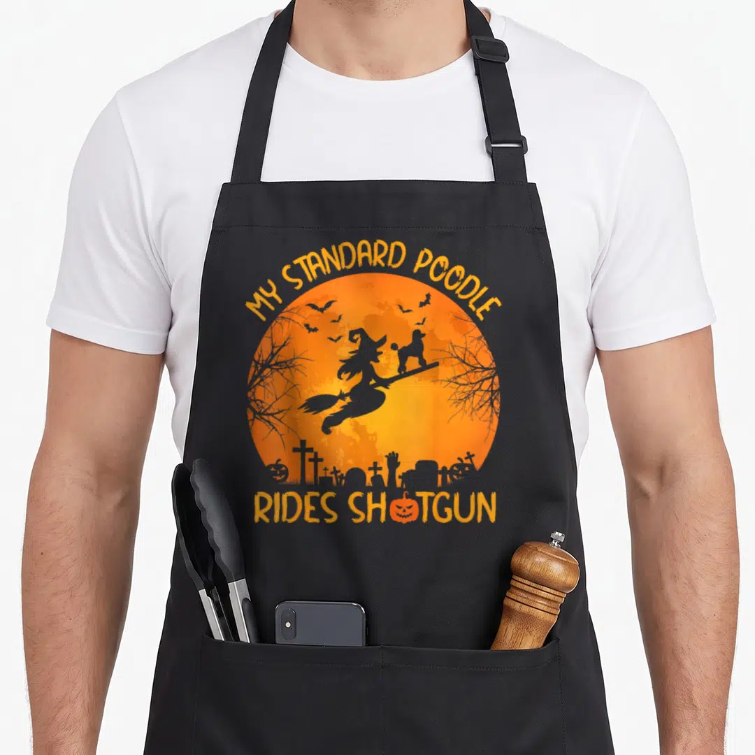 Ride standard size of apron - Orange moon with witch poodle silhouette and graveyard text My Standard Poodle Rides — shown on a black cotton canvas apron against a white background