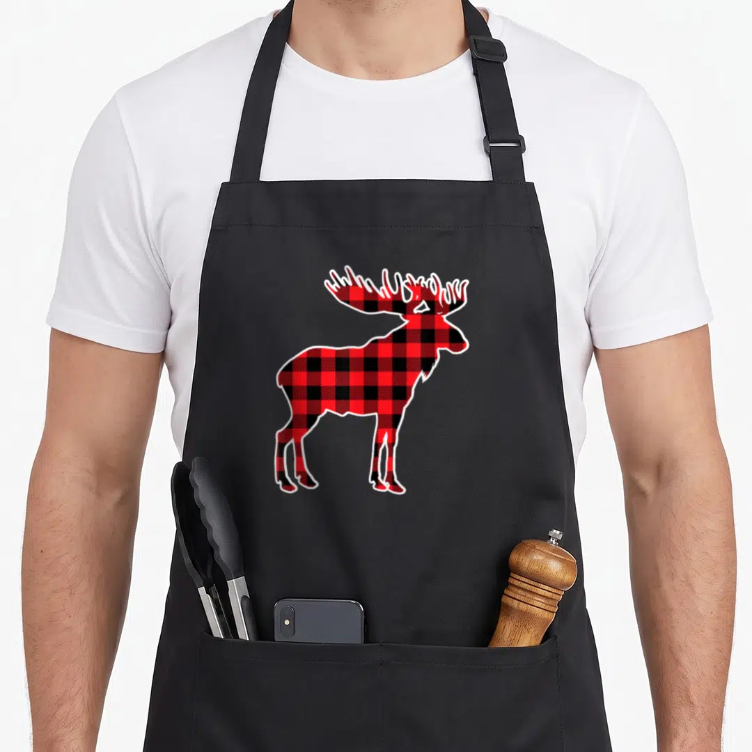 Moose red plaid apron - Cartoon moose silhouette filled with red black plaid pattern and white outline — shown on a black cotton canvas apron against a white background