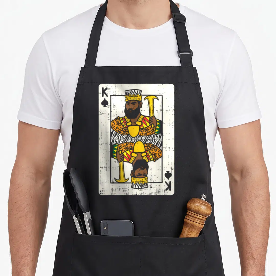Card african print apron - Retro King of Spades playing card design in yellow brown white and black — shown on a black cotton canvas apron against a white background