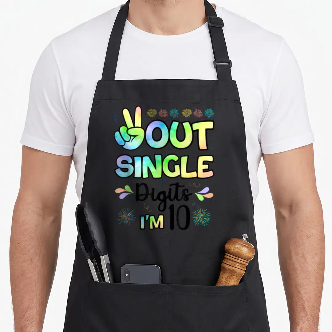 Peace double digits birthday apron - Colorful peace sign hand with OUT SINGLE Digits I'M 10 text and fireworks — shown on a black cotton canvas apron against a white background