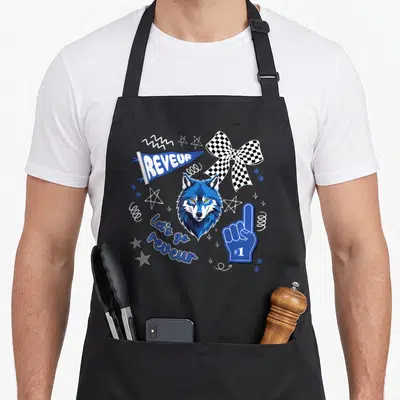 Reveur school apron - Blue wolf head with checkered bow, foam finger, and REVEUR pennant design — shown on a black cotton canvas apron against a white background