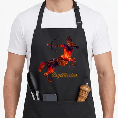 Sagittarius trending aprons - Fiery centaur drawing bow with gold Sagittarius text — shown on a black cotton canvas apron against a white background