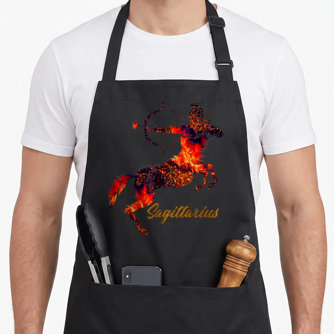 Sagittarius trending aprons - Fiery centaur drawing bow with gold Sagittarius text — shown on a black cotton canvas apron against a white background