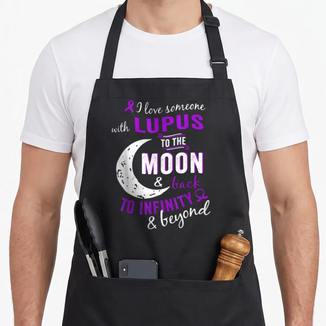 Symptom lupus awareness apron - Purple and white text reading I love someone with lupus to the moon and back — shown on a black cotton canvas apron against a white background