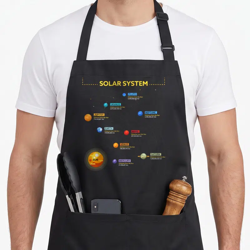 Solar geek apron - SOLAR SYSTEM title with nine planets showing distances from Sun in km, minimalist yellow blue orange — shown on a black cotton canvas apron against a white background